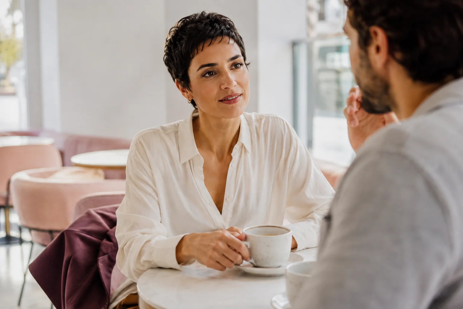 A woman chatting with her date across a small cafe table.