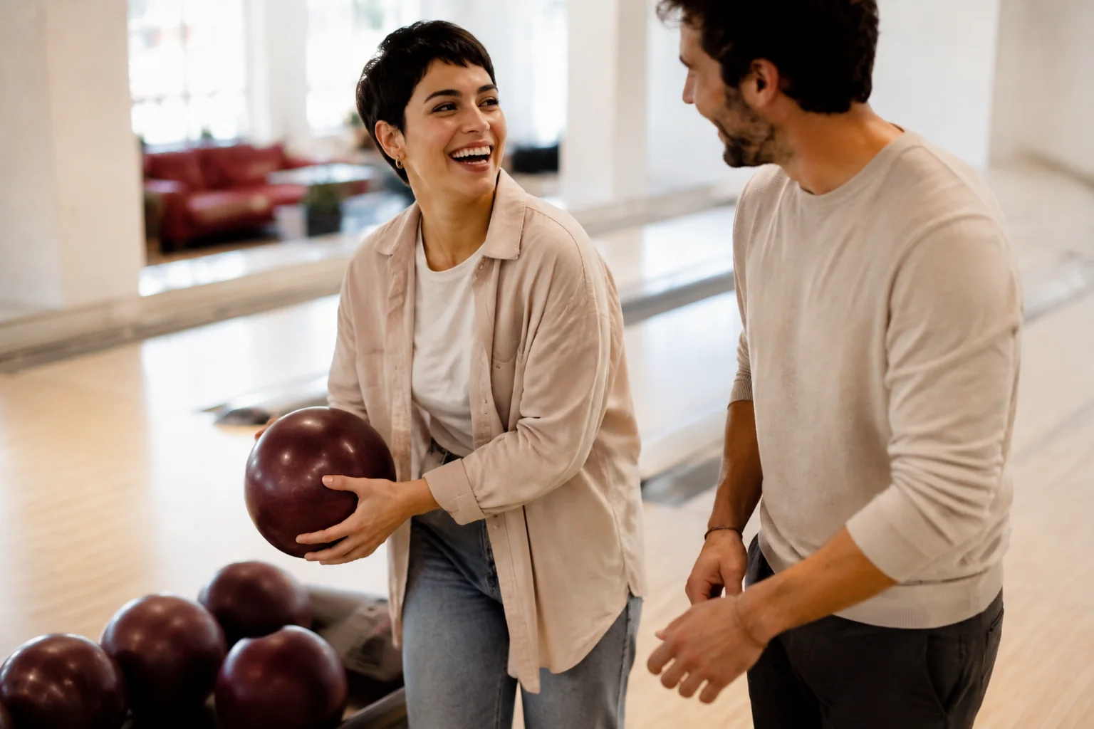 A woman laughing with her date while choosing a bowling ball.