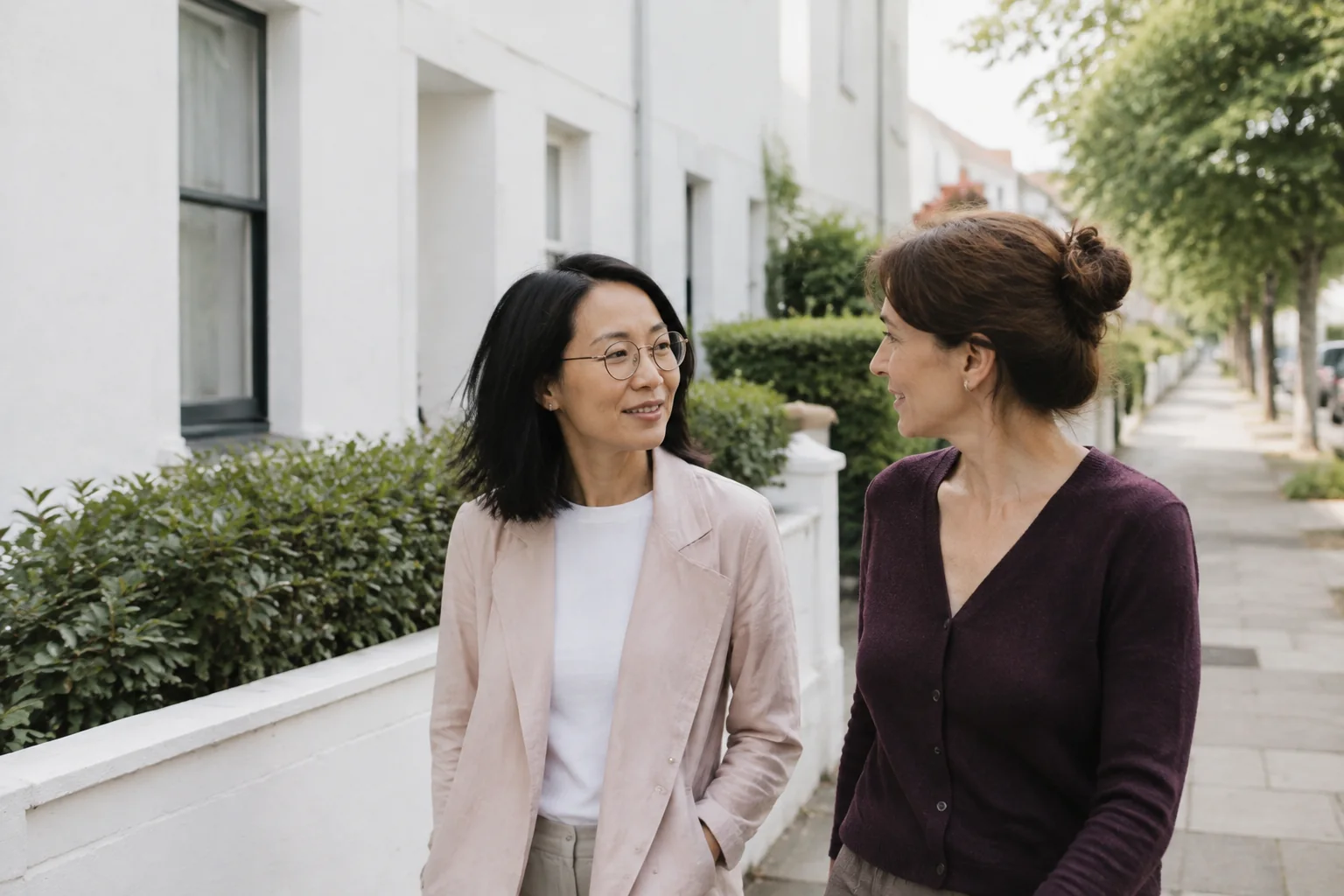 Two women walk together along a sunny neighbourhood path.