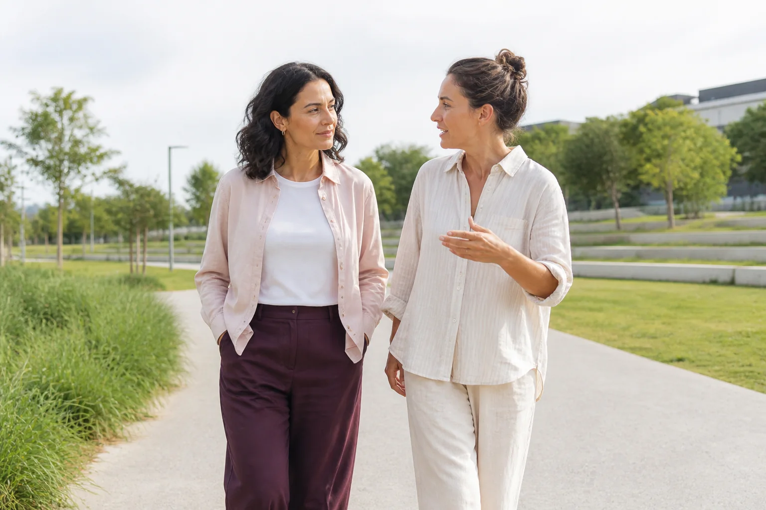A woman and a female friend talking while walking along a quiet park path.